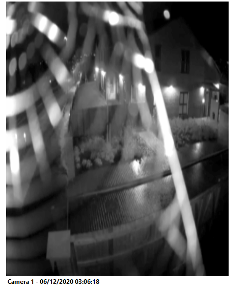 A spider web obscuring a camera lens at night, detected by automated image checks
